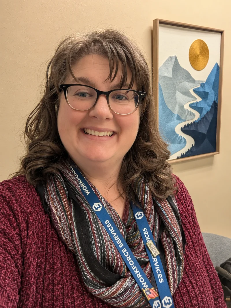 Melissa smiling in an office, wearing a burgundy cardigan